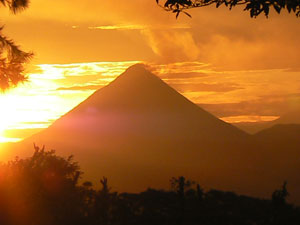 A brilliant sunrise illuminates Arenal Volcano as seen from these lots.